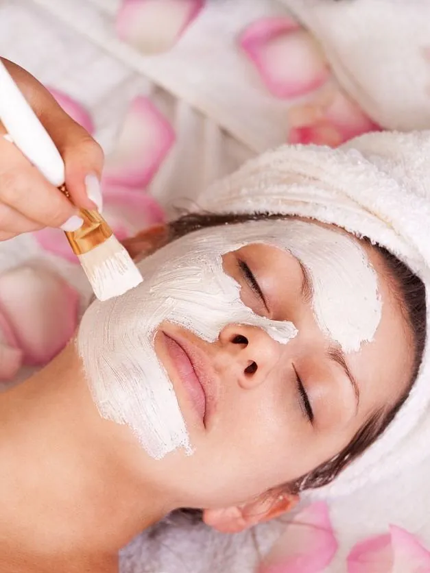 mujer con toalla cabeza se somete a tratamiento facial